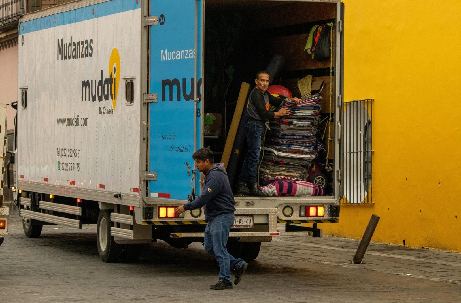 Workers loading a moving truck on a street in Mexico, urban lifestyle.