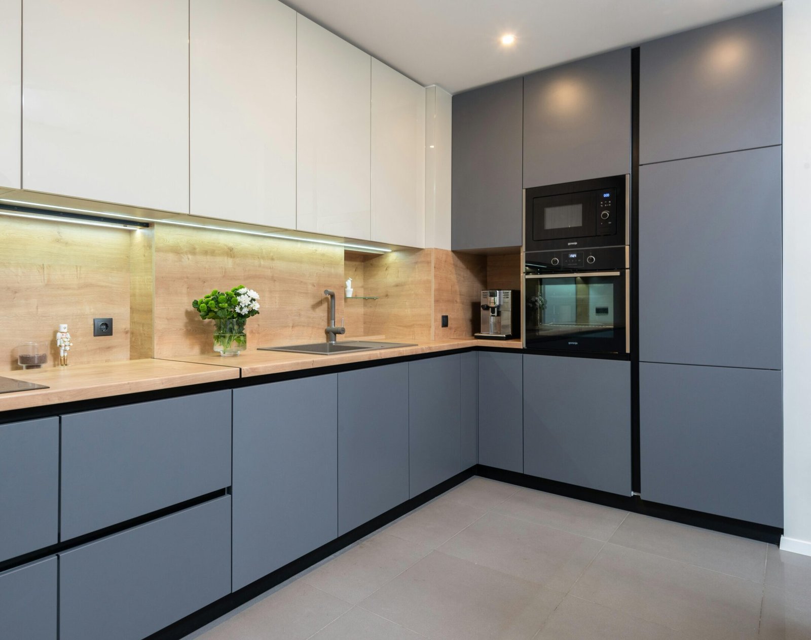 Creative design of kitchen with cupboards and built in oven against flowers in vase in light house